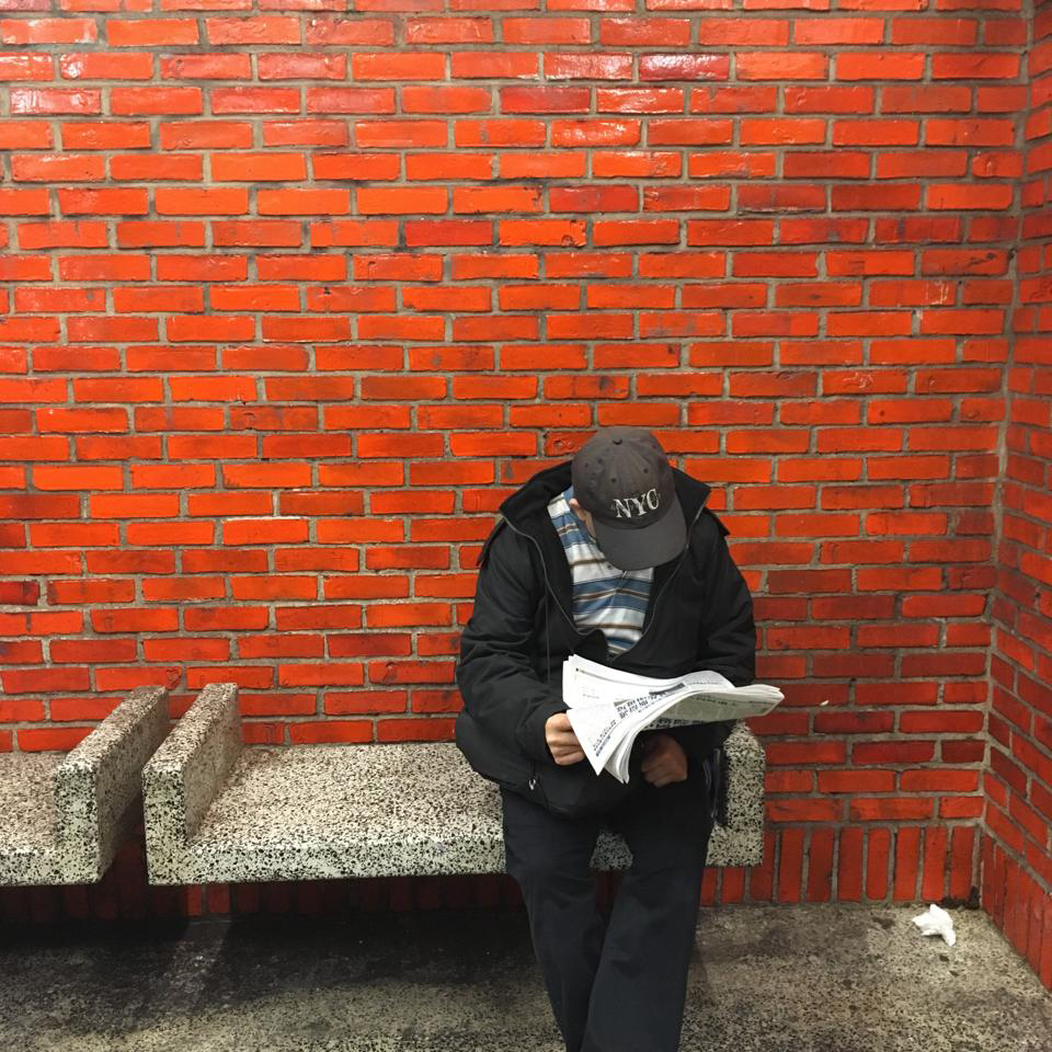 Mies lukee lehteä metrolaiturilla