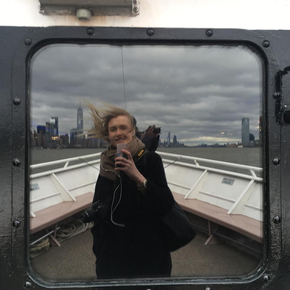 Nainen laivassa ja kaupungin siluetti taustalla